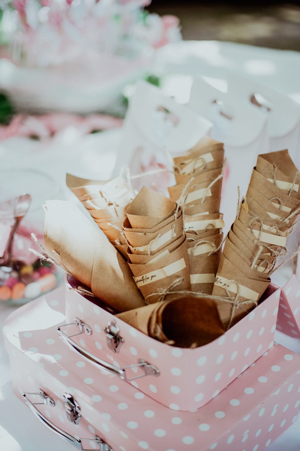 Coni di carta dorata pieni di confetti, dentro una scatola rosa a pois