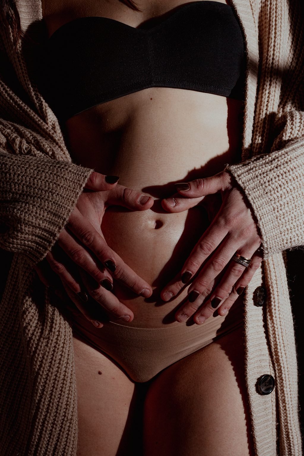 Le mani di lei, aperte a cuore sulla pancia, fra i lembi di un cardigan di lana