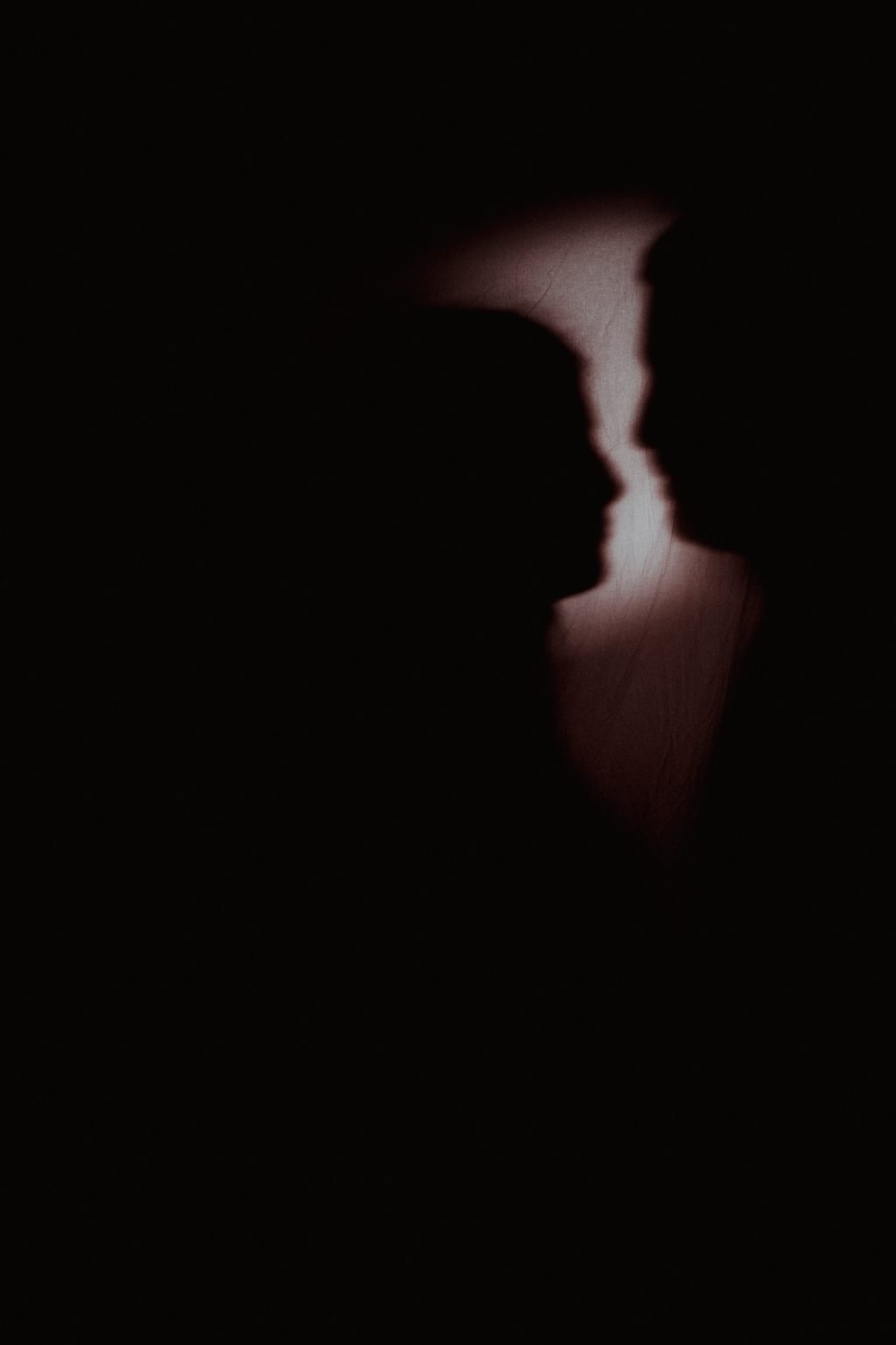 Due profili che si sfiorano, disegnati da una sottile lama di luce su fondo completamente nero