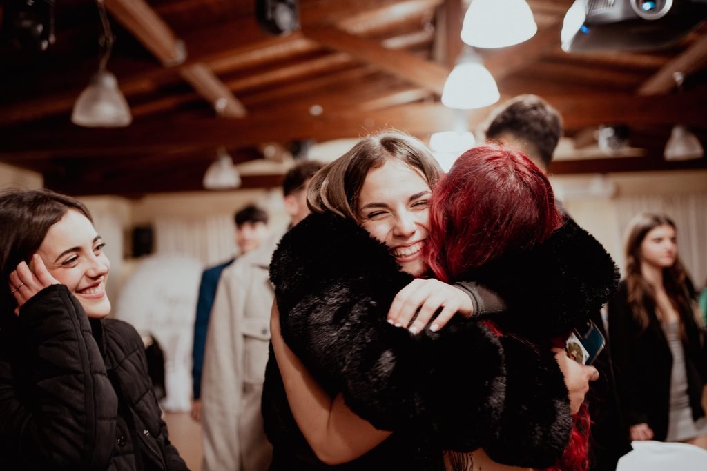 La festeggiata abbraccia forte un’amica, mentre gli altri invitati sorridono intorno