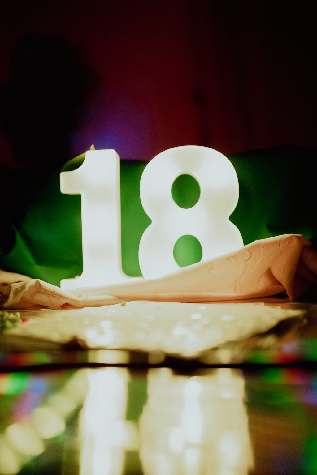 Il numero 18 luminoso appoggiato sul tavolo, fra le luci colorate della festa