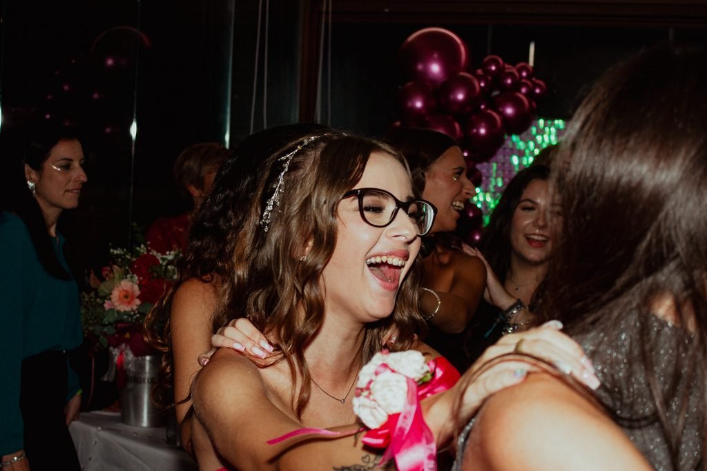 La festeggiata con gli occhiali e la coroncina ride stretta fra le amiche