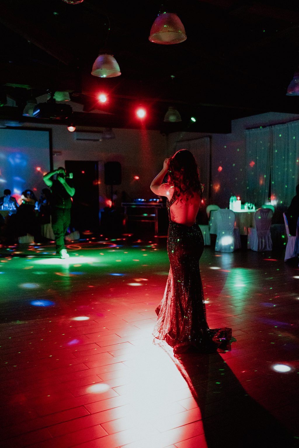 La festeggiata in abito verde al centro della pista, fra luci rosse e verdi da discoteca