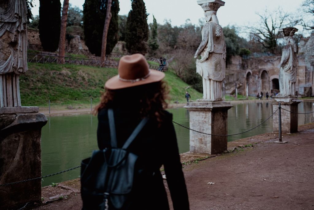 Nemi di spalle con il cappello e lo zaino guarda le statue delle cariatidi che si specchiano nel Canopo