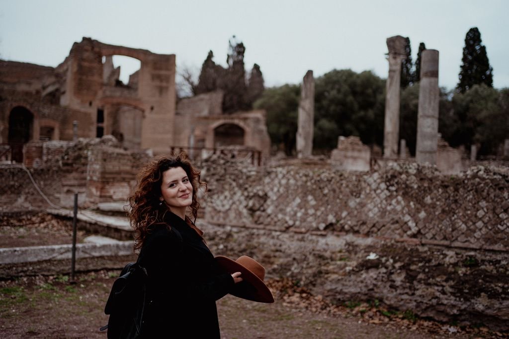 Nemi si volta e sorride con il cappello in mano, davanti alle rovine e alle colonne
